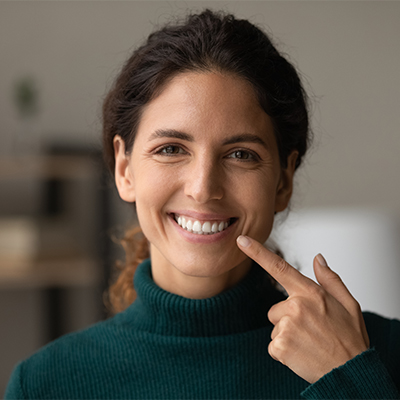 Woman pointing to her healthy and happy smile.