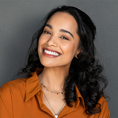 A young woman with a genuine, happy smile posing against a simple background.